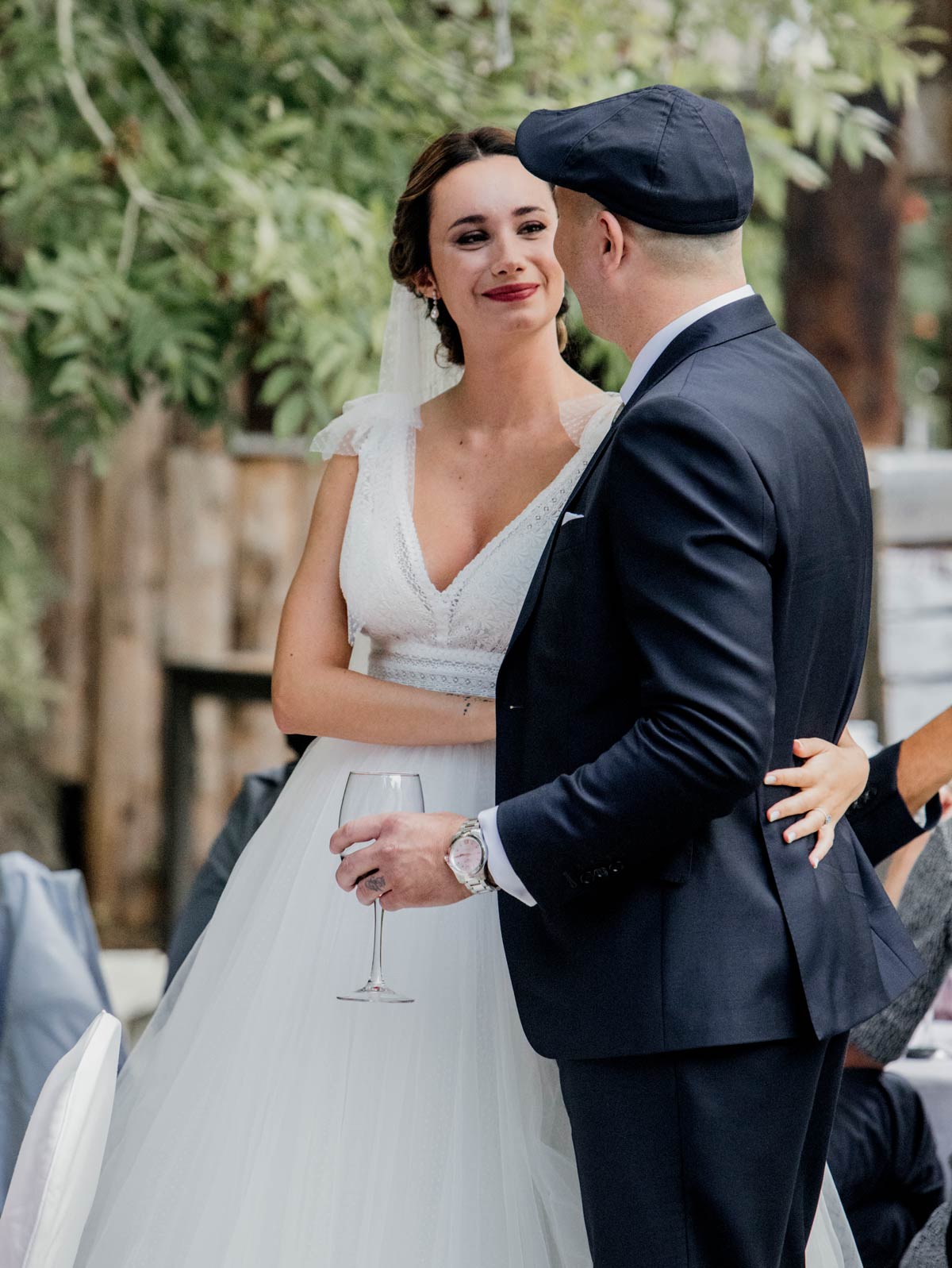 Novia y novio abrazados mientras brindan en un momento emotivo de su boda al aire libre en Bilbao.