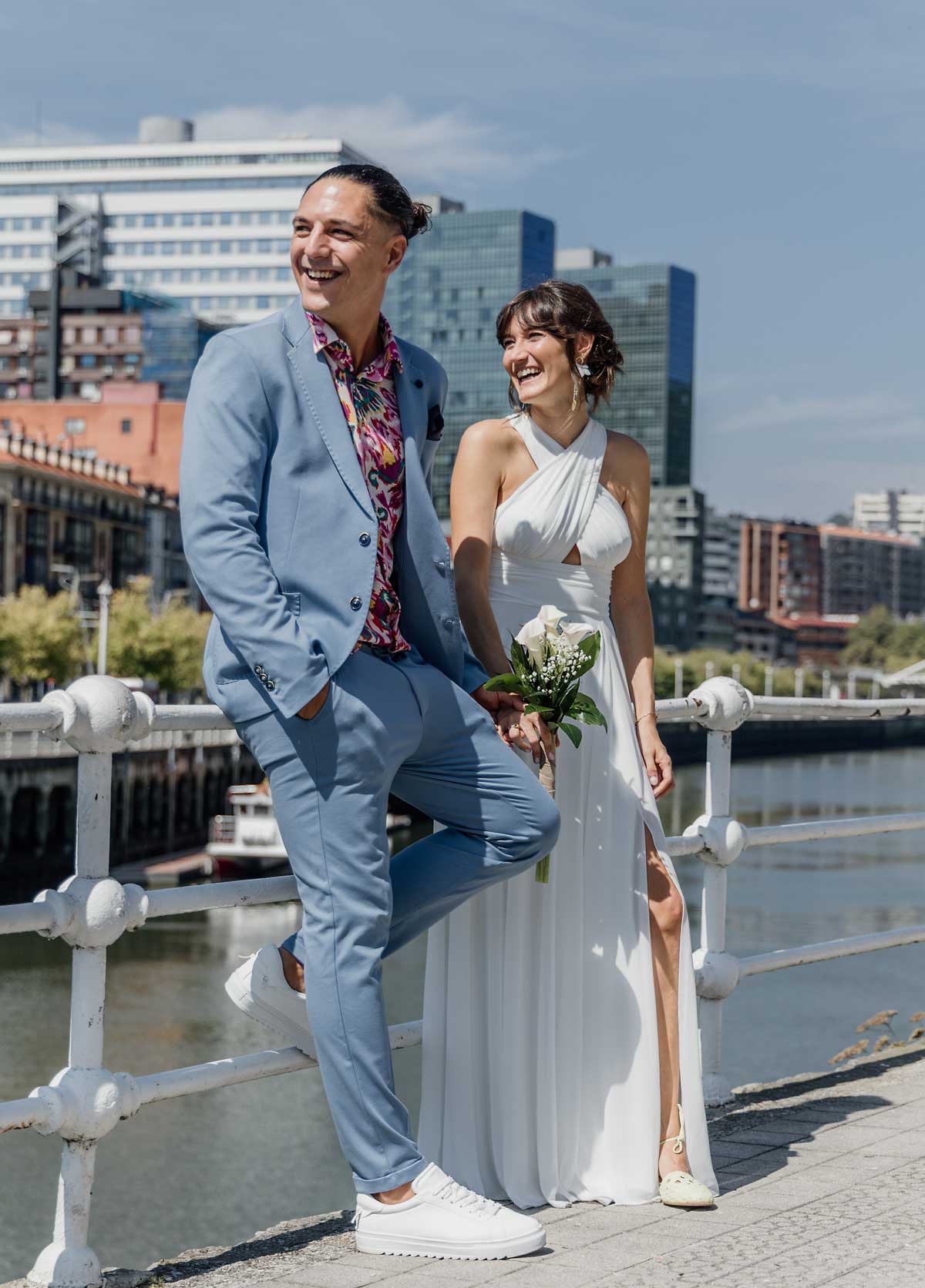 Pareja de recién casados posando junto a la ría de Bilbao en un día soleado, fotografía de boda en Bizkaia.