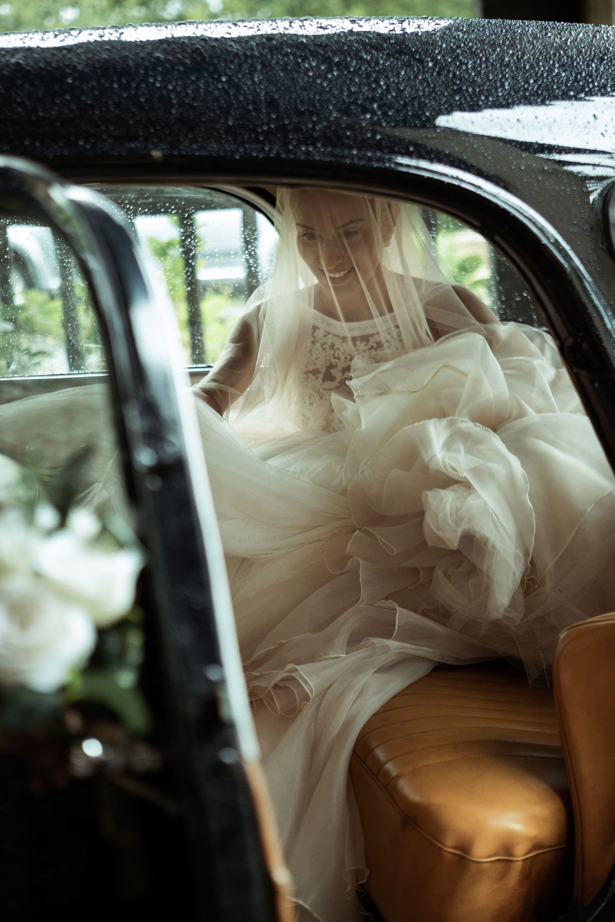 Novia entrando en un coche clásico durante una boda en Bizkaia, fotografía artística de estilo documental.