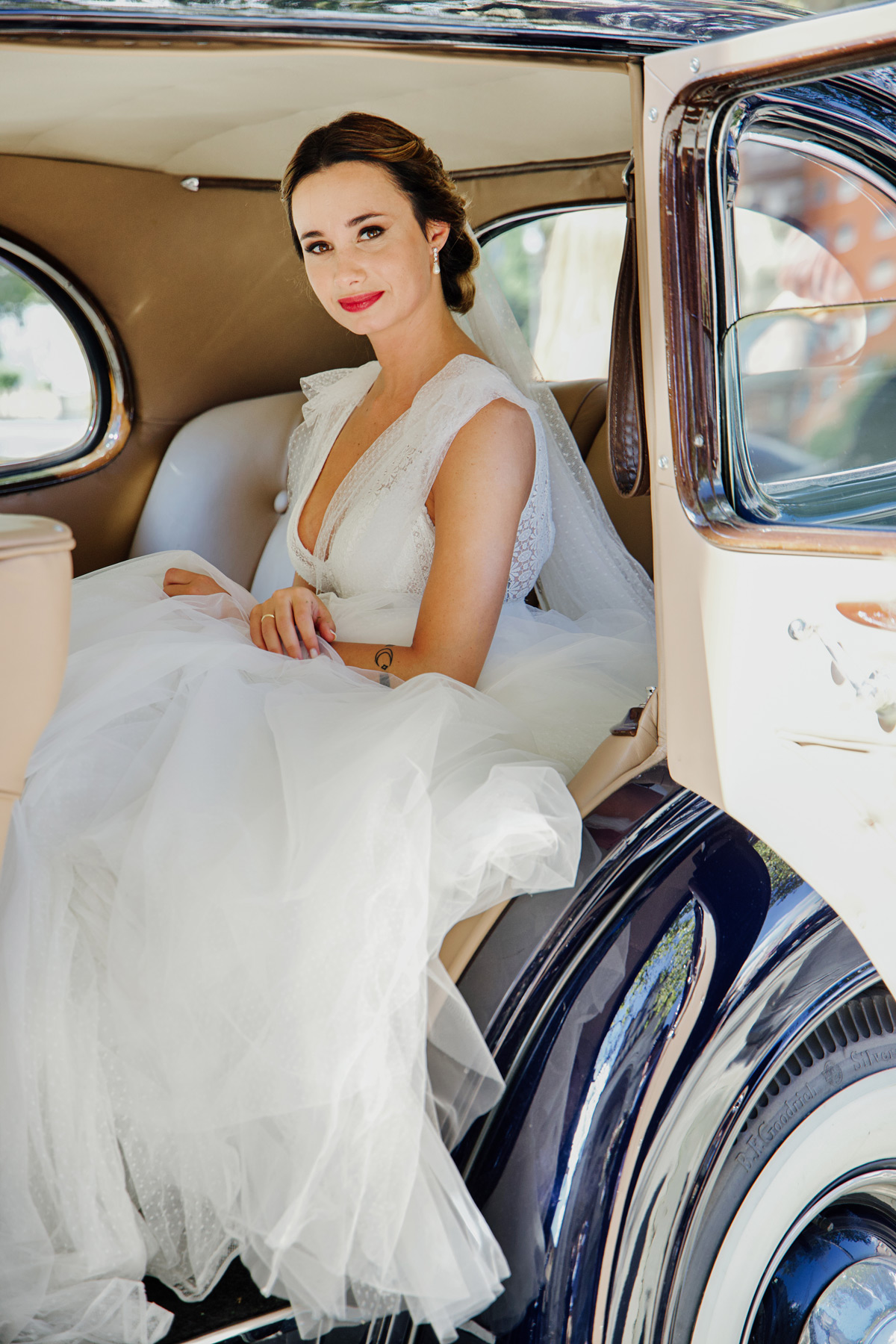 Novia sentada en un coche clásico el día de su boda, fotografía de estilo elegante realizada cerca de Bilbao.