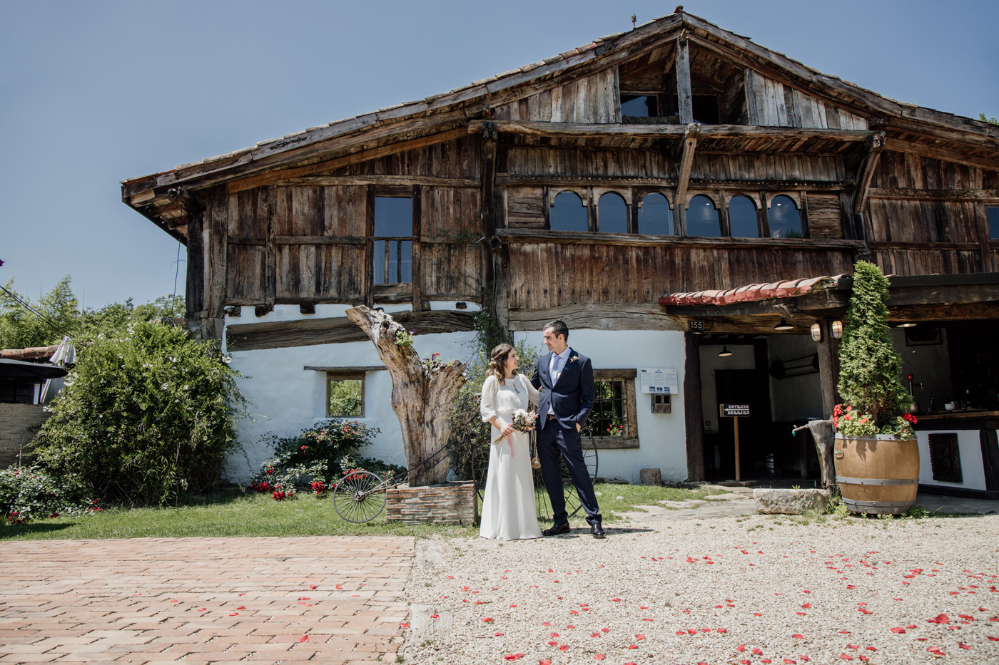 Pareja de boda posando frente al caserío tradicional del restaurante Aspaldiko en un entorno rural con luz natural.