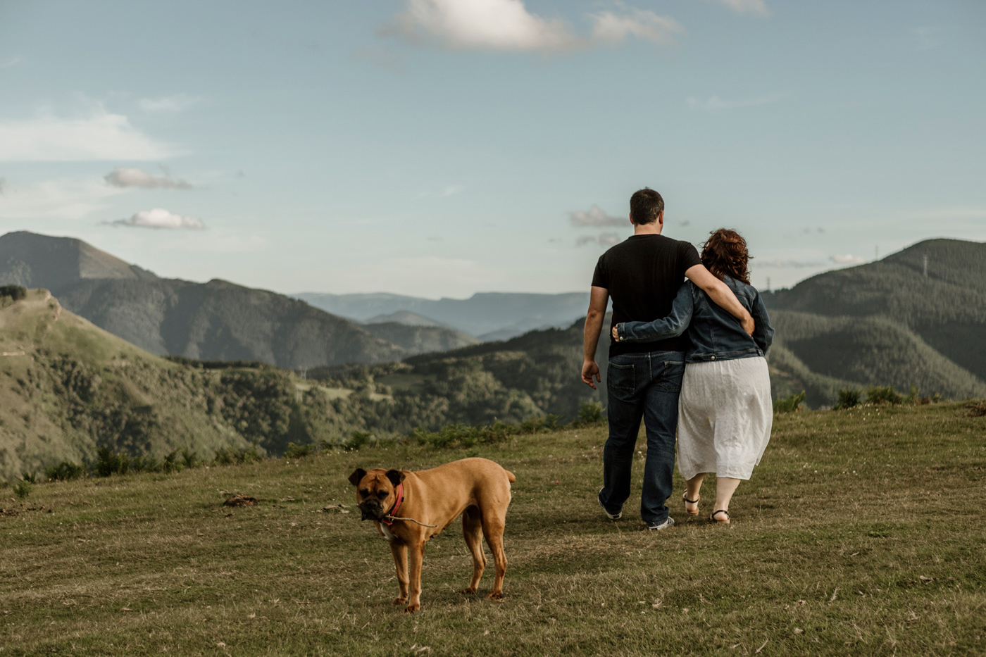 Fotografía de preboda en la naturaleza con una pareja y su mascota en un paisaje de montaña.
