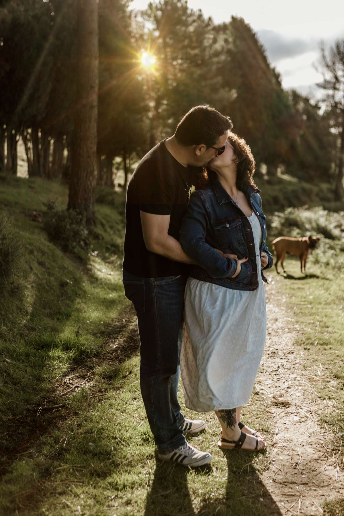 Sesión preboda en Asturias con pareja besándose entre árboles al atardecer.