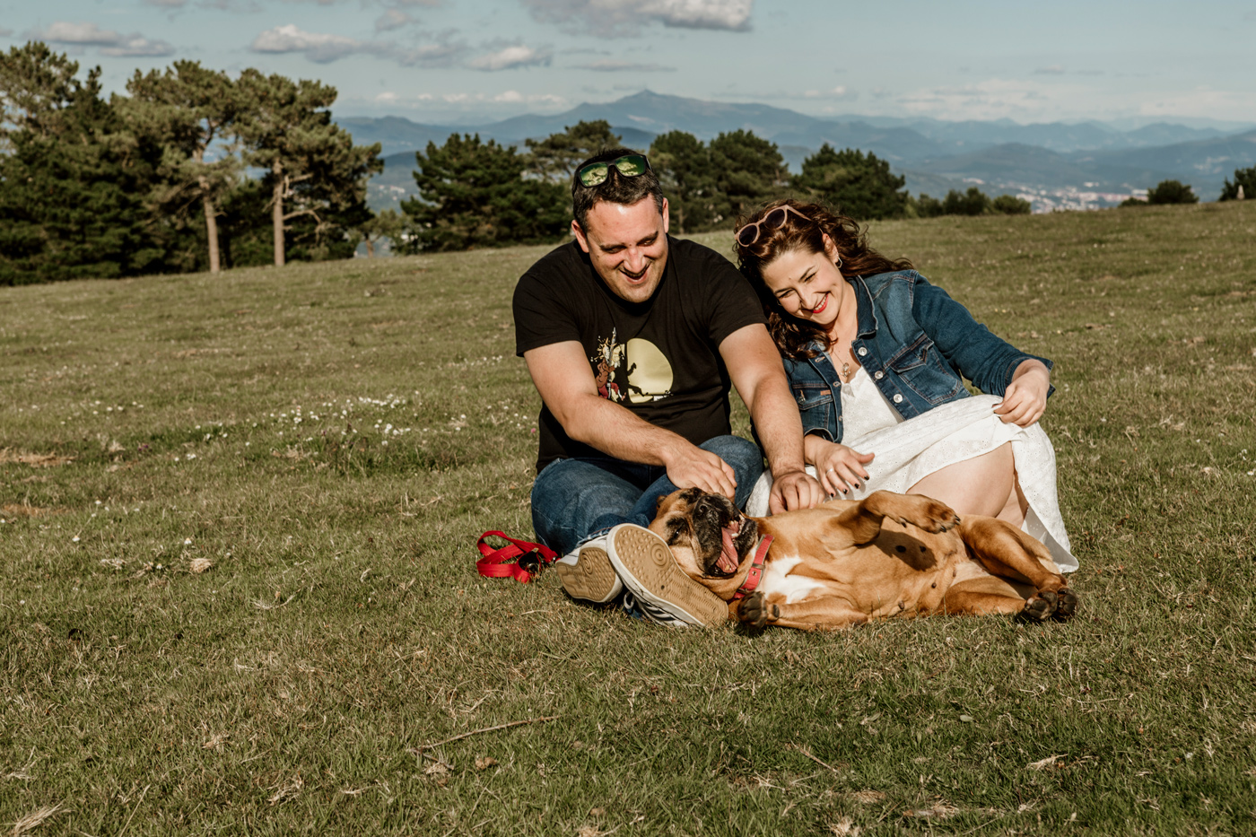 Pareja acariciando a su perro en una sesión de preboda al aire libre en Bizkaia.