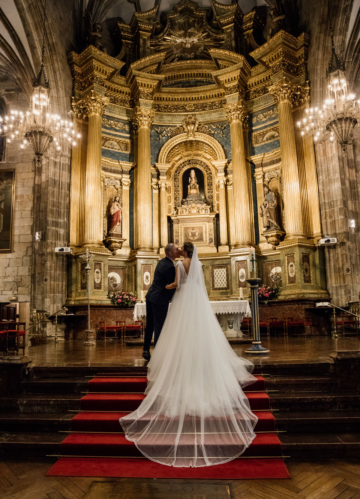 "Pareja de recién casados abrazándose frente al altar de una iglesia con un retablo dorado."