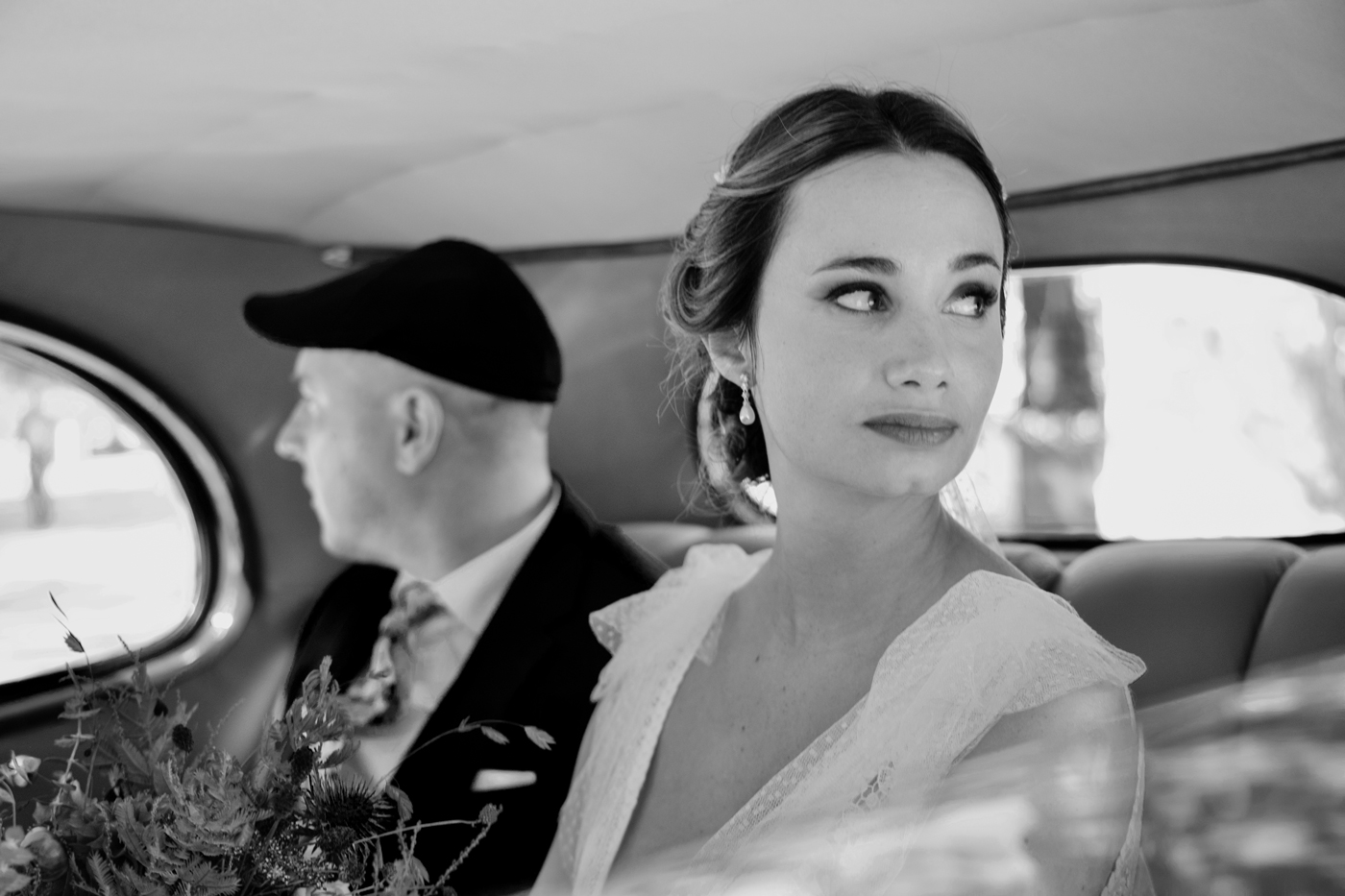 Novia mirando por la ventanilla dentro de un coche clásico camino a la ceremonia, fotografía de boda estilo documental