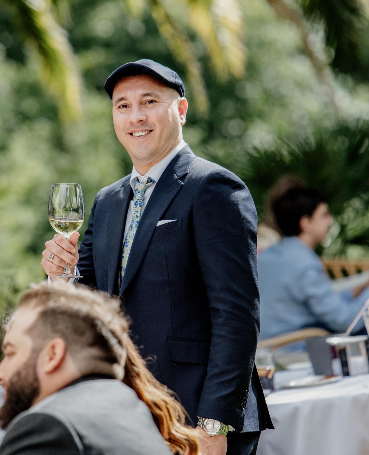 Invitado sonriendo durante el cóctel de la boda mientras sostiene una copa de vino.