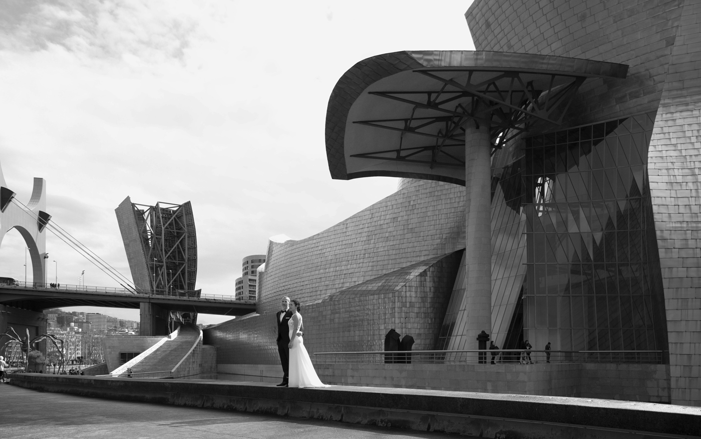 Pareja de novios posando frente al Museo Guggenheim de Bilbao durante su boda — fotografía artistica en blanco y negro de North Producciones