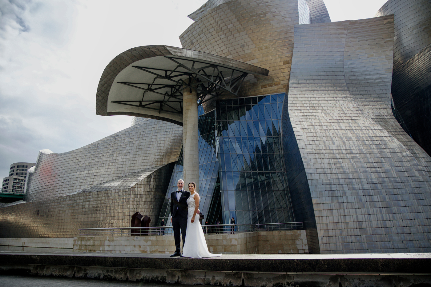 Pareja de boda posando frente al Museo Guggenheim de Bilbao en un reportaje fotográfico elegante y moderno.
