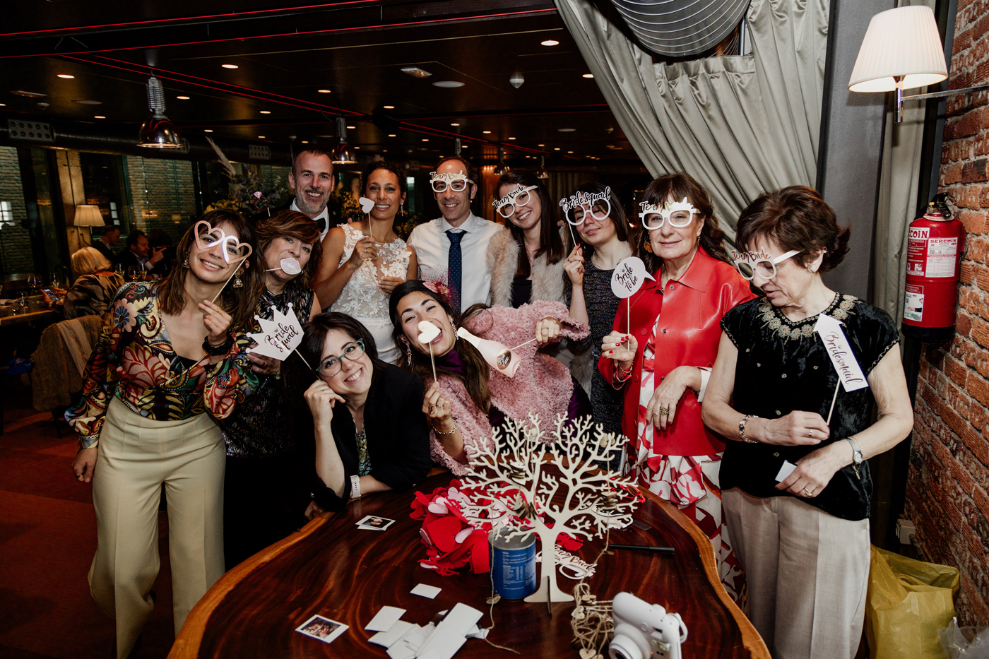 Grupo de invitados y los novios posando con accesorios divertidos durante el photocall de una boda en Bilbao, fotografía realizada por un fotógrafo de bodas en Bilbao.