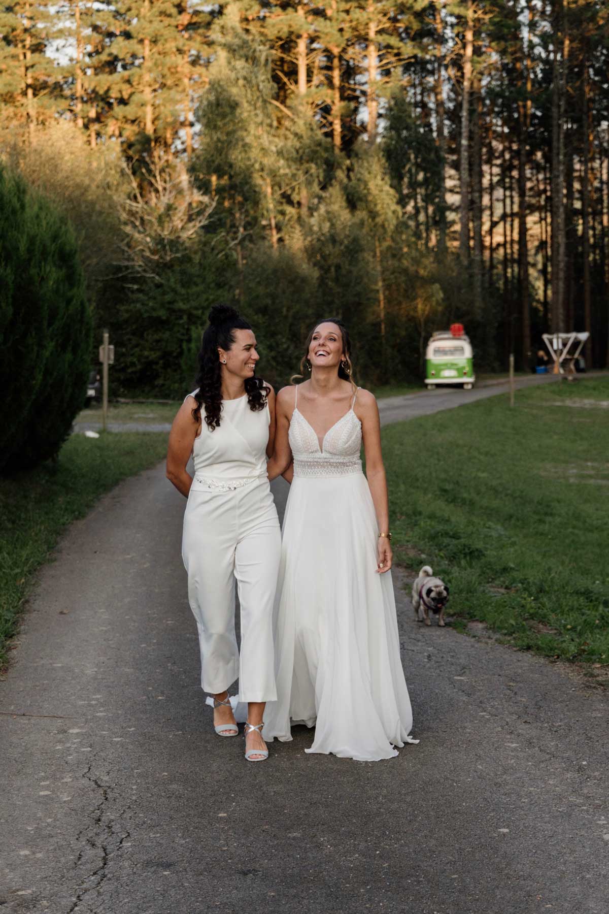 "Pareja caminando juntas con vestidos de boda en un entorno natural de Bizkaia durante una sesión fotográfica."