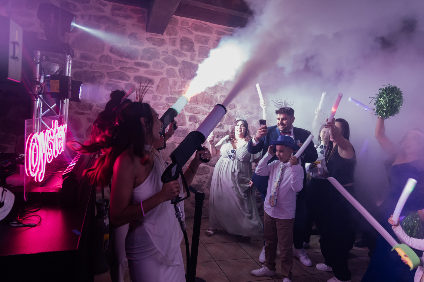 "Celebración de boda en Bizkaia con efectos de humo y luces, grupo de invitados disfrutando durante la fiesta."