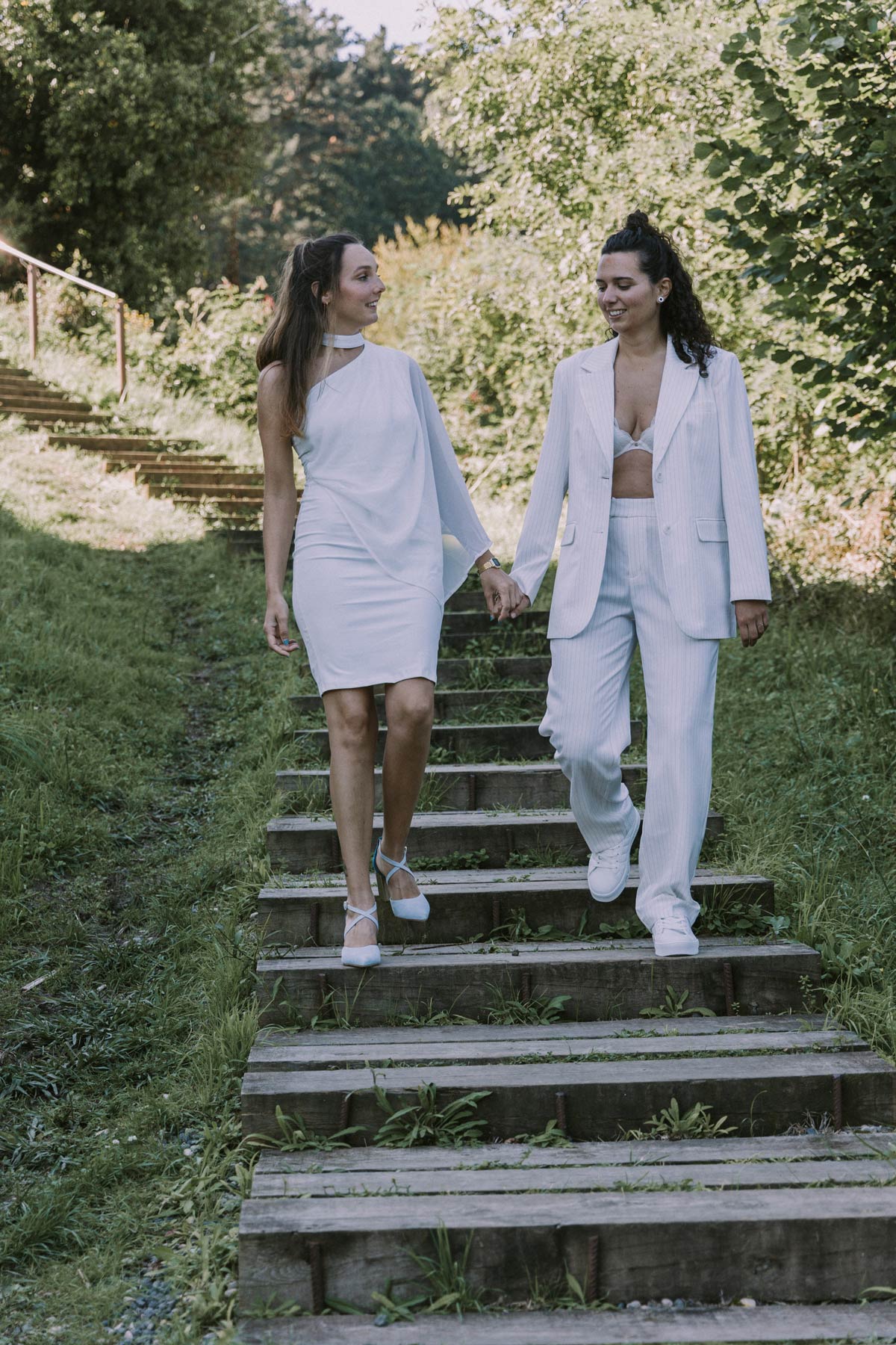 Pareja de novias caminando juntas por un sendero natural durante su boda, fotografiadas por un fotógrafo de bodas en Bilbao y Bizkaia.