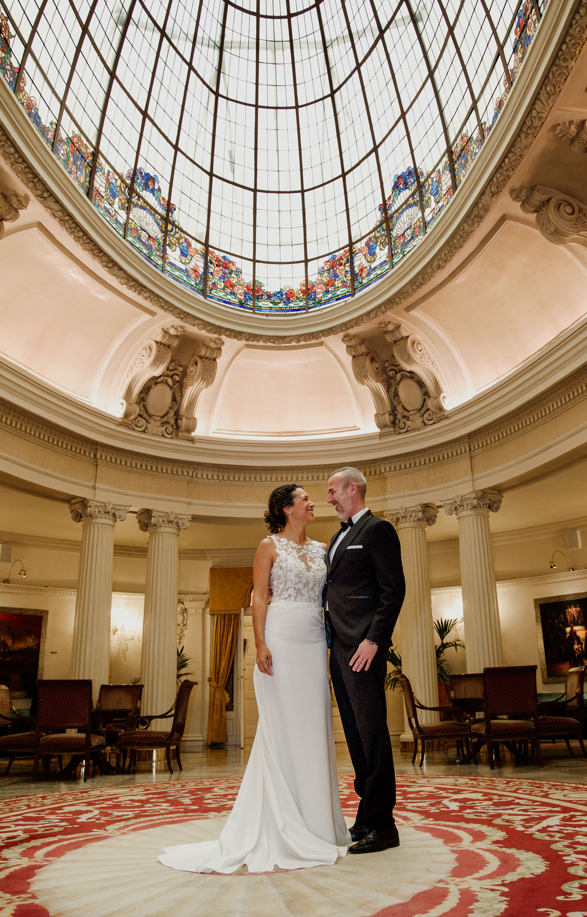 Pareja de recién casados posando en un elegante salón con cúpula de cristal durante su boda, fotografía realizada por un fotógrafo de bodas en Bilbao.