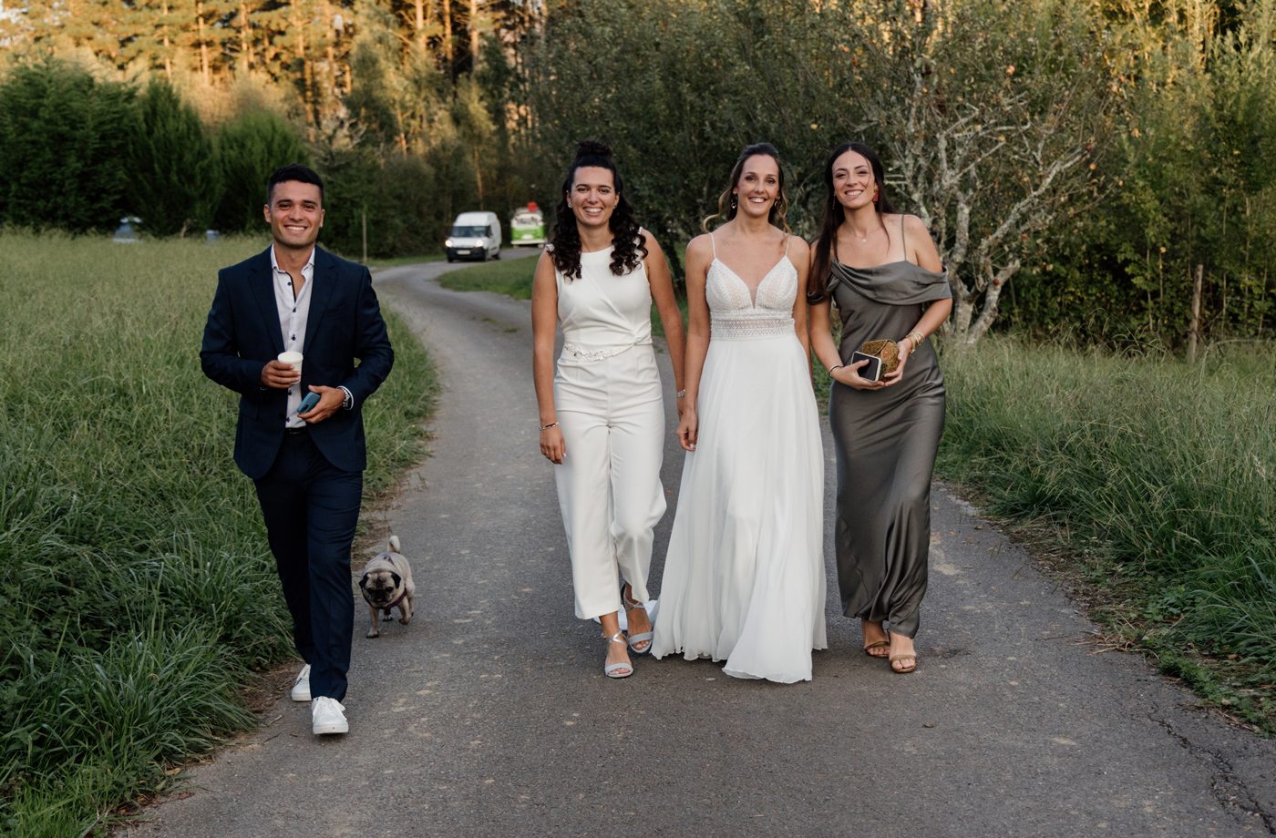 "Pareja de novias caminando junto a familiares por un camino rural durante una boda en Gipuzkoa."