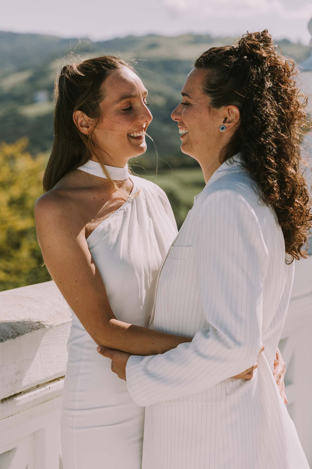 Pareja de novias abrazadas y sonriendo durante su boda al aire libre, fotografiadas por un fotógrafo de bodas en Bilbao y Bizkaia.