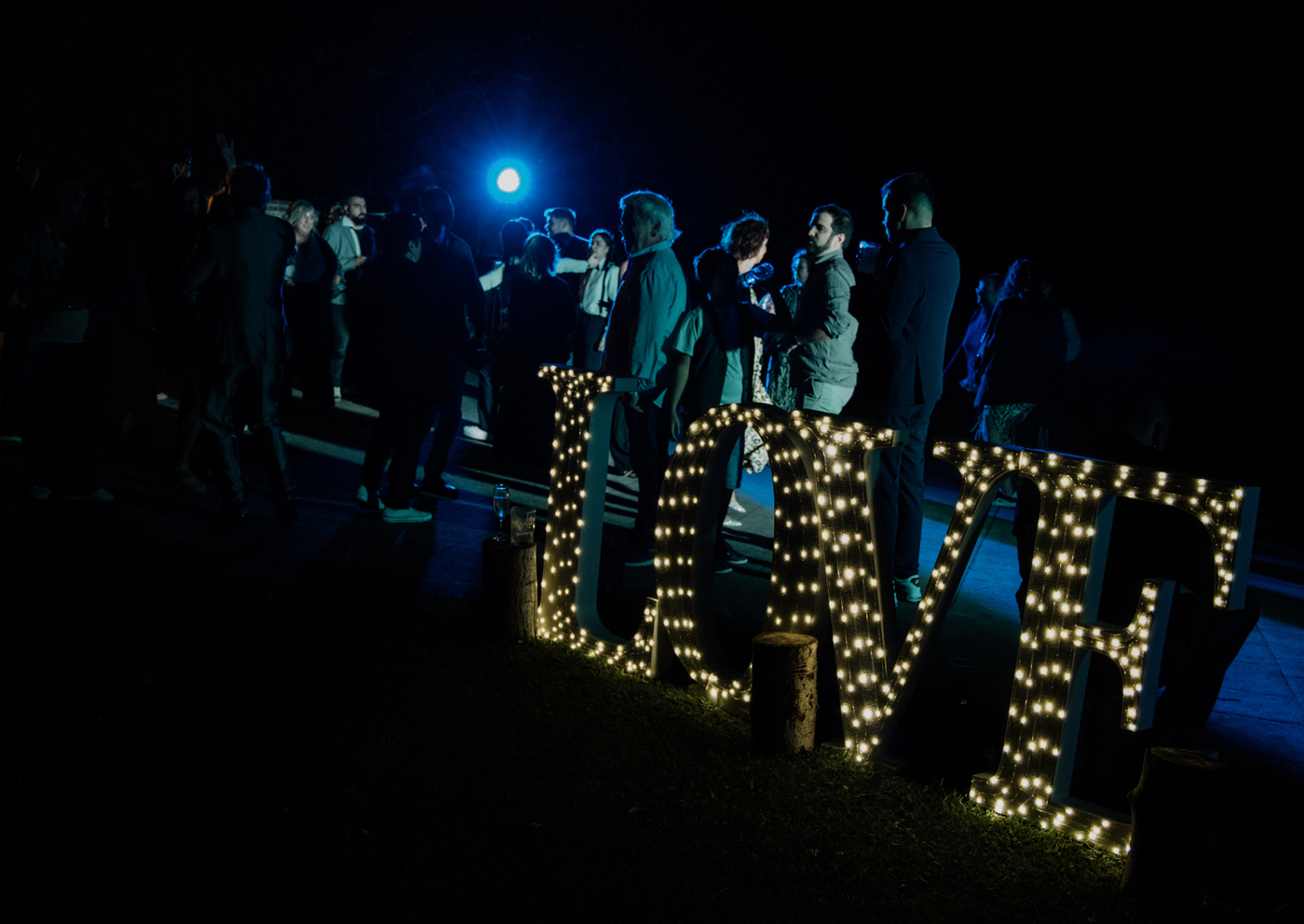 "Letras luminosas LOVE y grupo de invitados celebrando durante una boda nocturna en Amorebieta, Bizkaia."