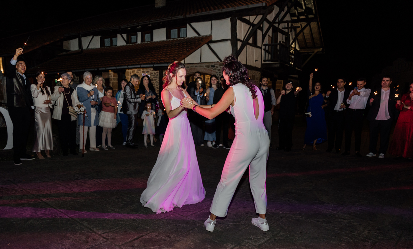 "Dos novias bailando de noche rodeadas de invitados durante su boda en Asturias."