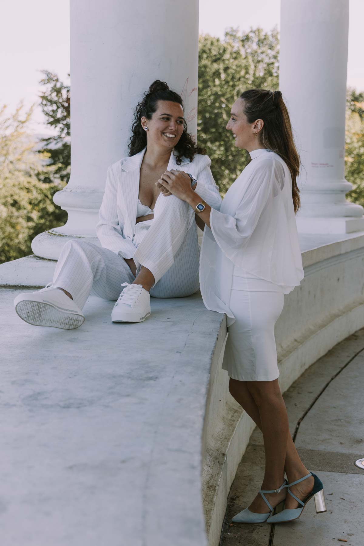 Pareja de novias conversando y riendo en un pórtico blanco durante su sesión de boda, fotografía realizada por un fotógrafo de bodas en Barakaldo, Bilbao y Bizkaia.
