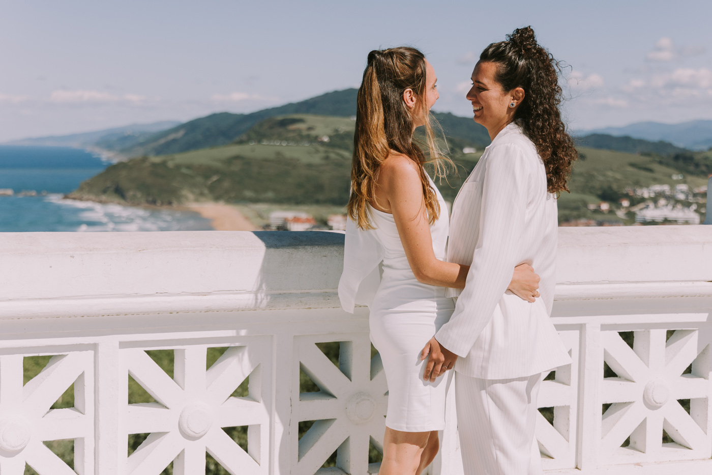 Pareja de novias abrazándose en un mirador con vistas a la costa, fotografía de boda realizada por un fotógrafo de bodas en Bilbao y Bizkaia.