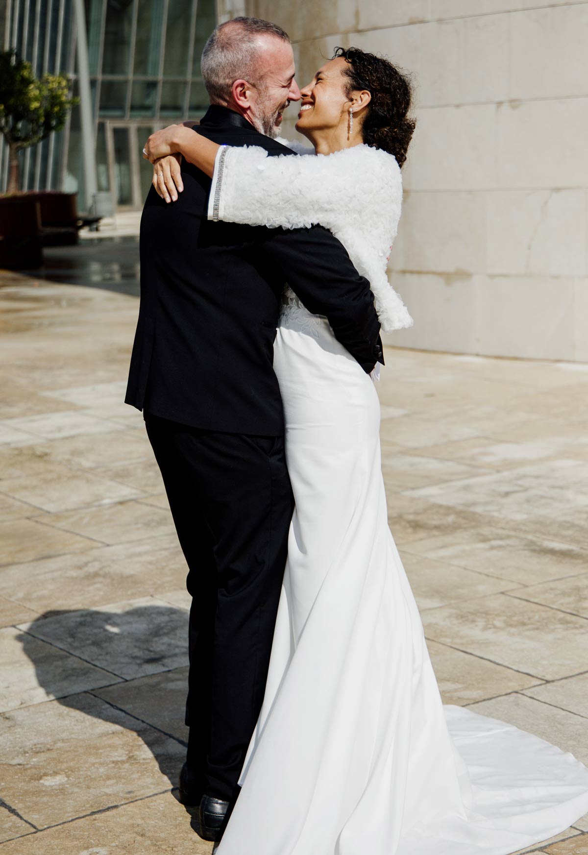 Novios abrazándose con emoción en un entorno exterior moderno, fotografia capturada por un fotógrafo de bodas en Cantabria.