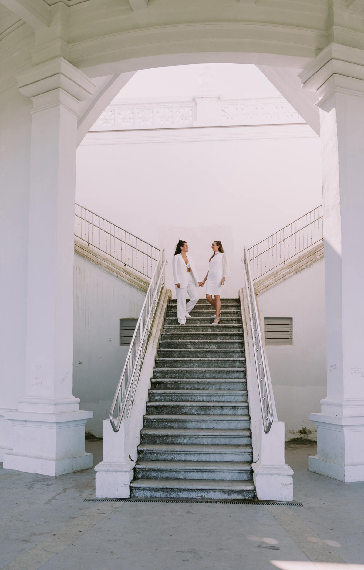 Pareja de novias bajando una escalera blanca durante su sesión de boda, fotografiada por un fotógrafo de bodas en Bilbao y Bizkaia.