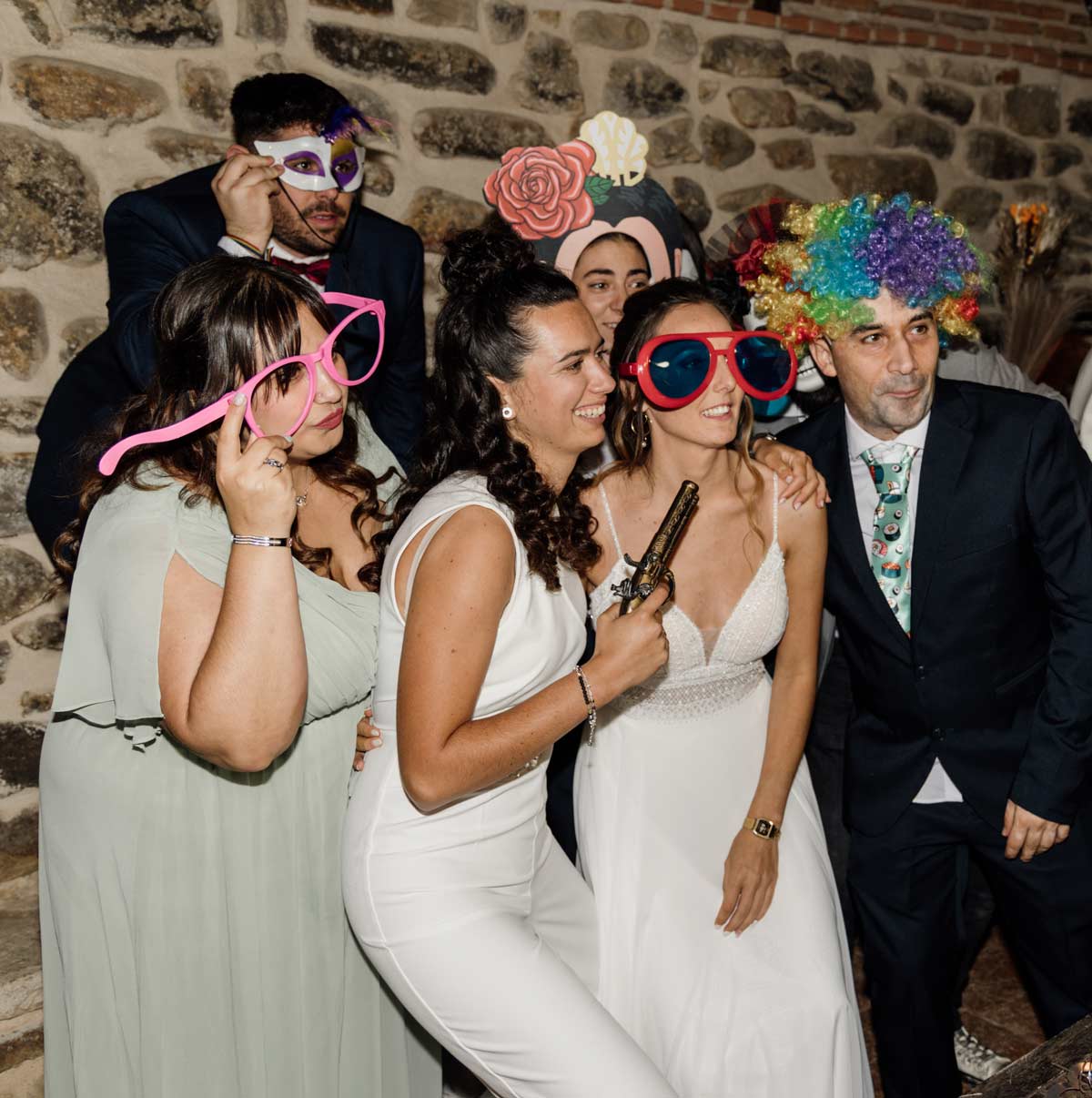 "Grupo de invitados y novias posando con disfraces y accesorios divertidos durante la fiesta de una boda, fotografía de boda en Bizkaia."
