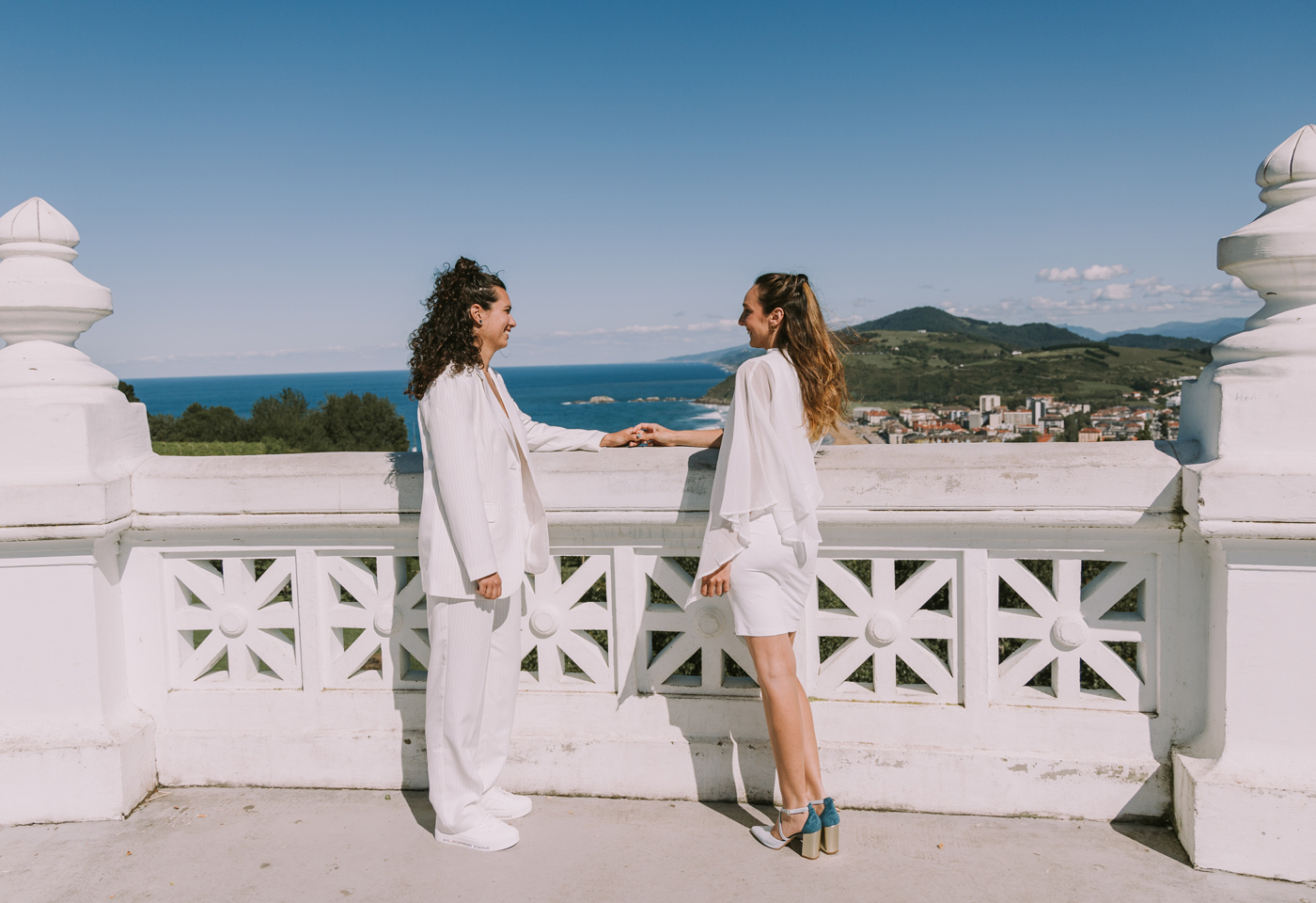 Pareja de novias disfrutando de su sesión de boda con vistas a la costa de Guipúzkoa en un día soleado.