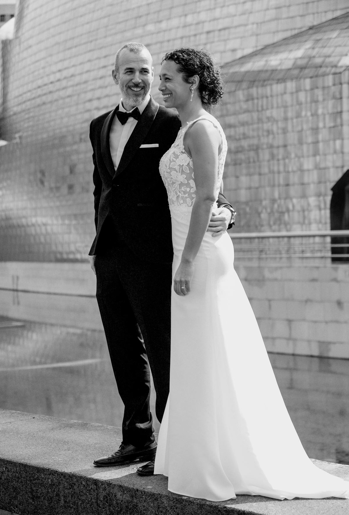 Novios posando frente a una fachada moderna del Guggenheim en una imagen elegante capturada por un fotógrafo de bodas de lujo en Bilbao.