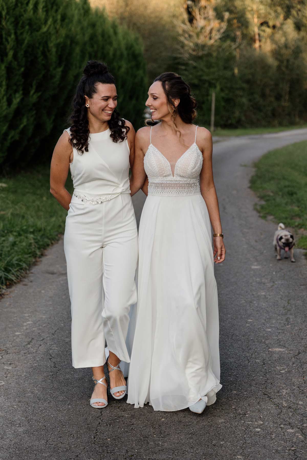 "Dos novias caminando juntas al aire libre el día de su boda, fotografía natural de boda en Bizkaia."