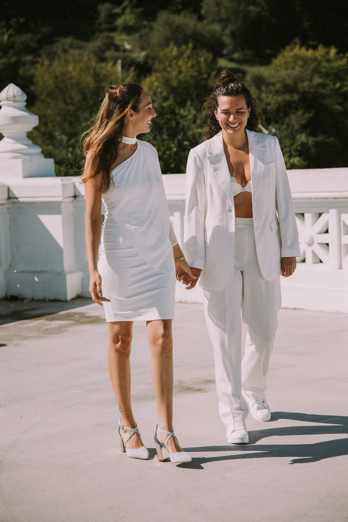 Pareja de novias caminando de la mano al aire libre durante su boda en Zarautz, fotografía natural y luminosa.