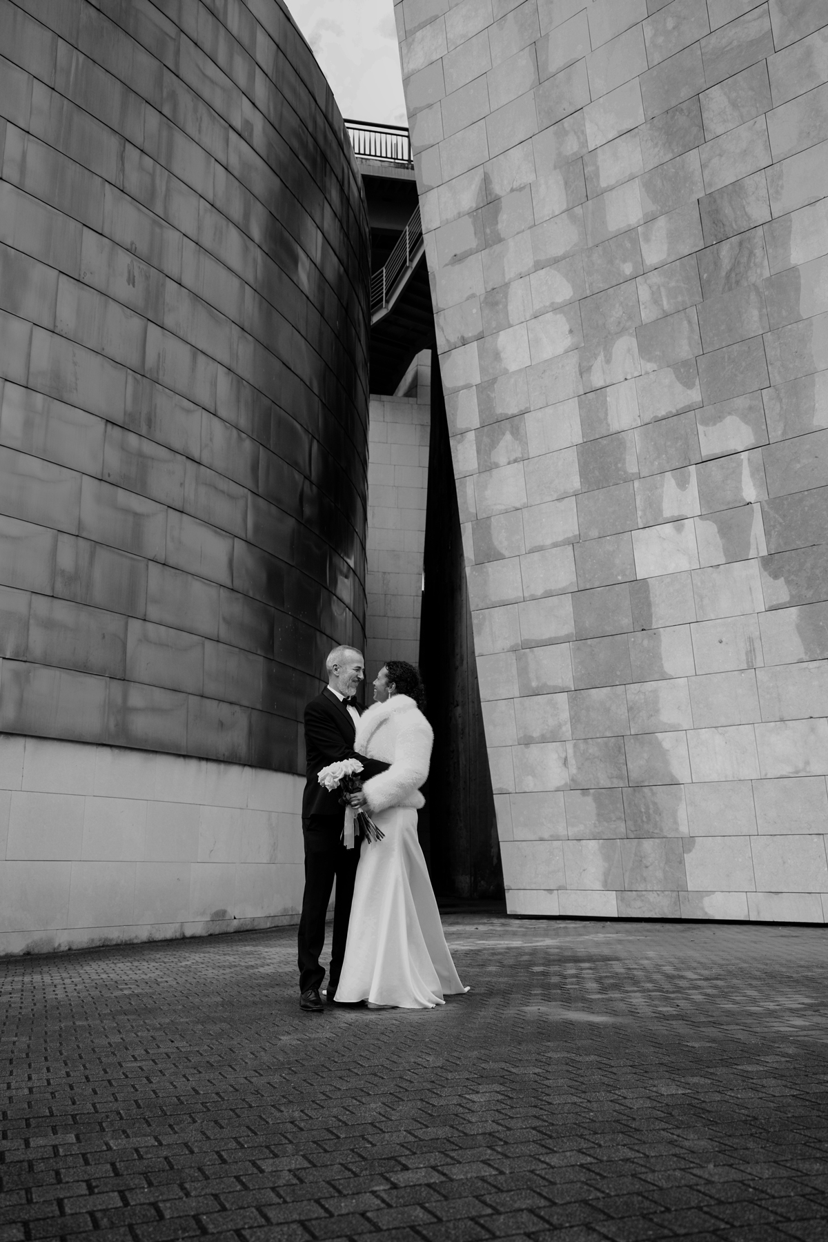 Pareja de novios posando entre arquitectura moderna, fotografía realizada por un fotógrafo de bodas en Bilbao.