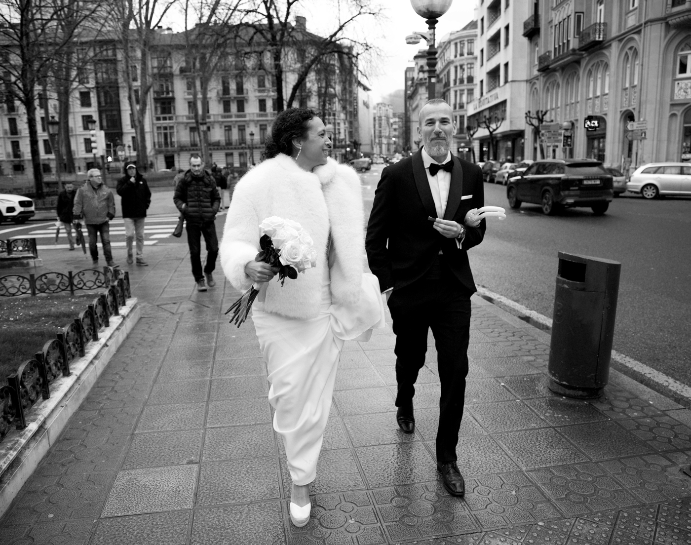 Pareja de boda caminando por una calle de Bilbao en un reportaje fotográfico de estilo documental en blanco y negro.