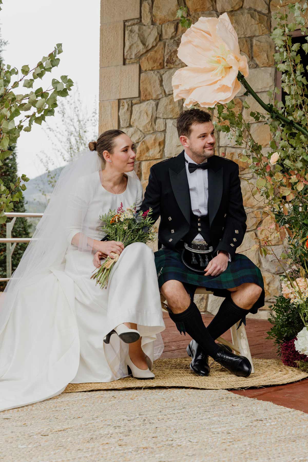 Pareja de novios sentados juntos durante su boda en un entorno rústico en Bizkaia-fotográfia natural y elegante de North Producciones