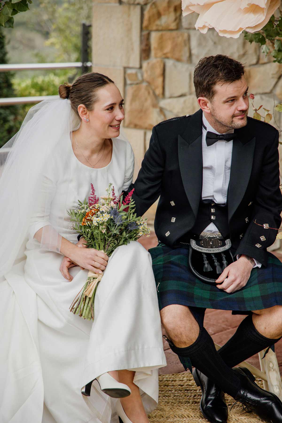 Novios sentados y sonriendo durante su boda en Bizkaia, fotografía natural captada por fotógrafo de bodas en Bizkaia.