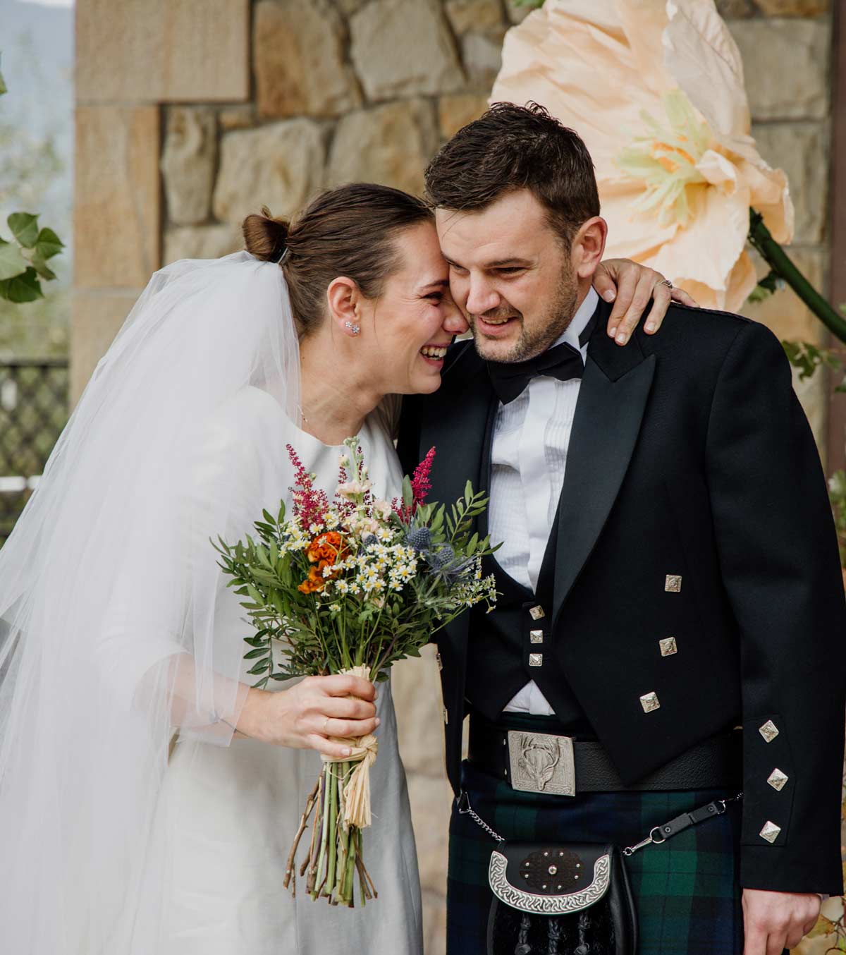 Novios abrazados y sonriendo con un ramo de flores durante su boda en Bizkaia, fotografía natural y emotiva de North Producciones.
