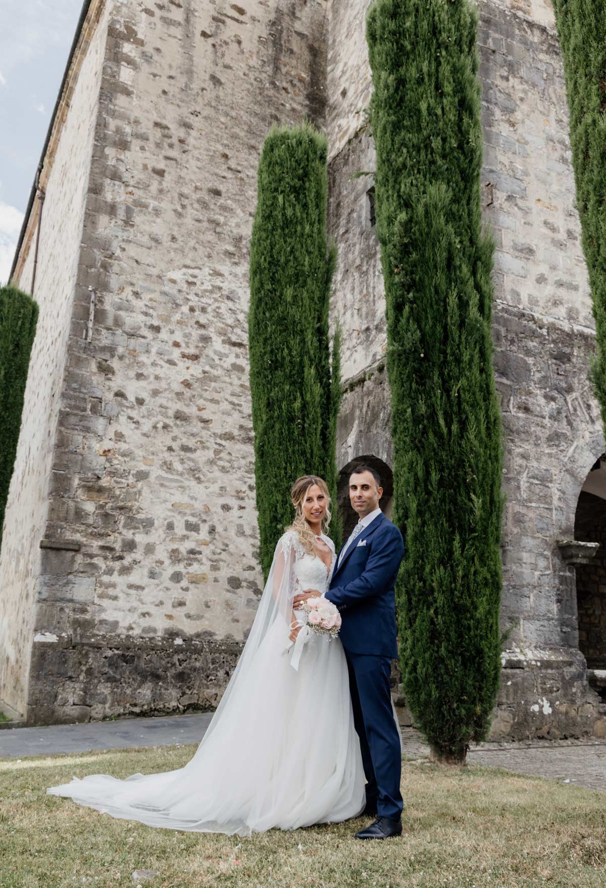 Pareja de recién casados posando junto a una iglesia de piedra durante su reportaje de boda - fotografía de bodas en Bilbao.