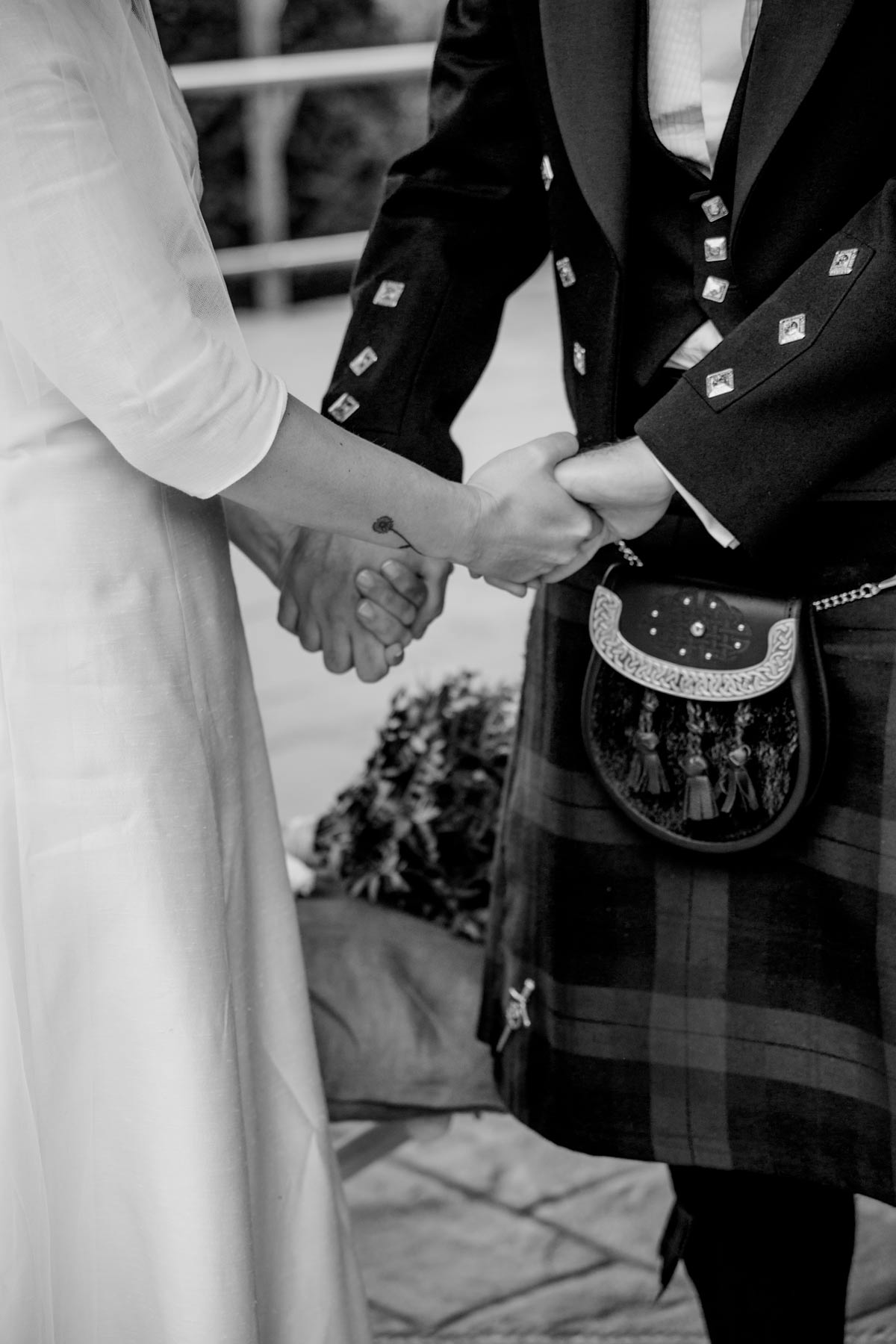 Detalle de los novios cogidos de la mano durante su boda en Bizkaia, fotografía en blanco y negro de estilo documental.