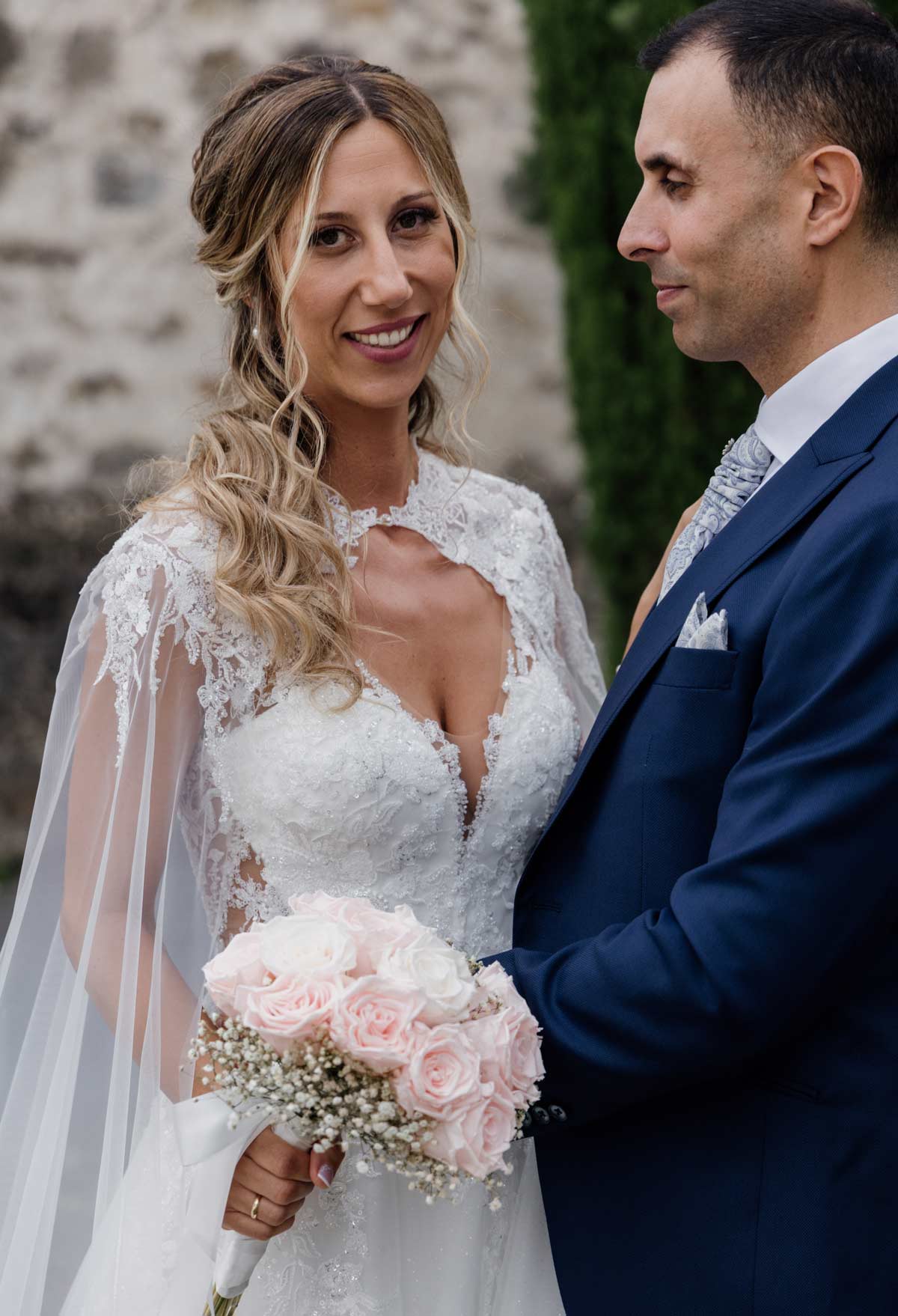 Novios mirándose con complicidad durante la sesión de boda, la novia sostiene un ramo de rosas - fotografía de bodas en Bilbao.