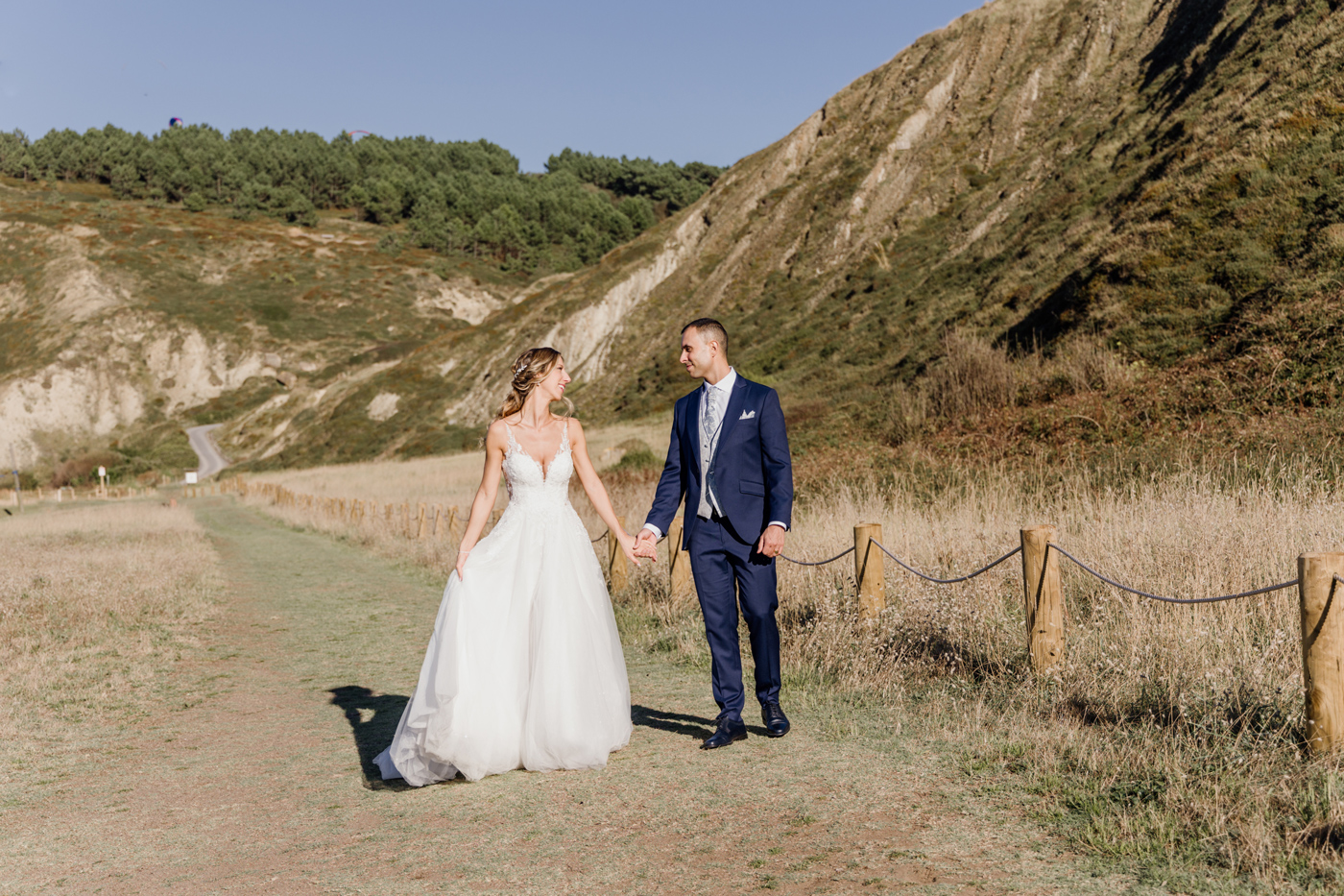 Pareja de novios caminando de la mano en un paisaje natural con montañas en Bizkaia - Fotógrafo de bodas en Bilbao y Bizkaia.