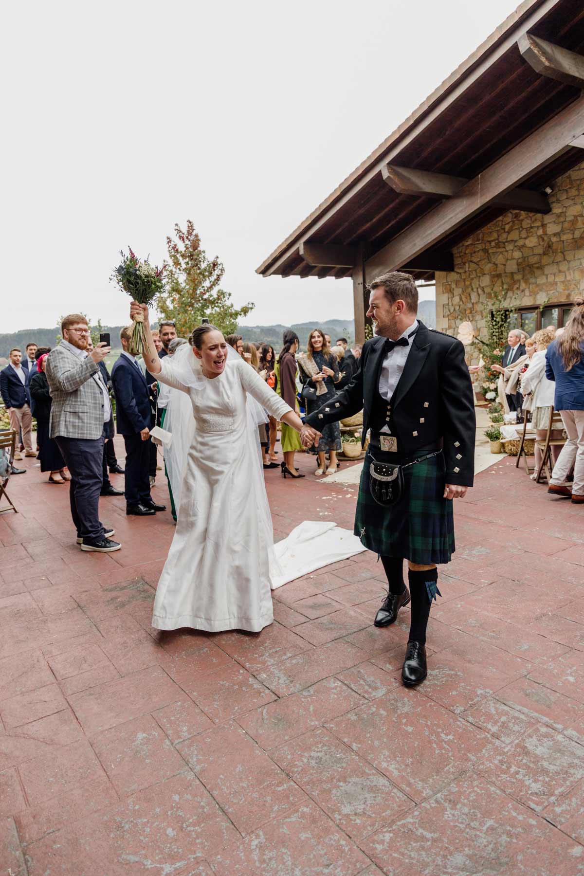 Pareja celebrando su boda al aire libre en Bizkaia, caminando entre invitados tras la ceremonia.