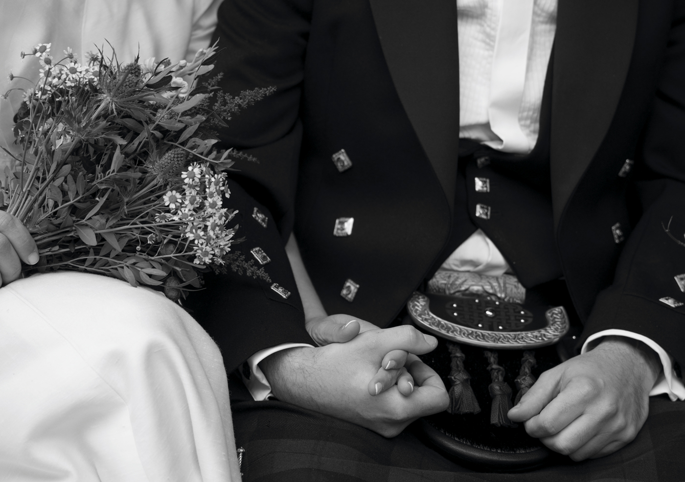 Primer plano de los novios tomados de la mano durante su boda, con ramo y traje tradicional, fotografía de boda en Bizkaia.