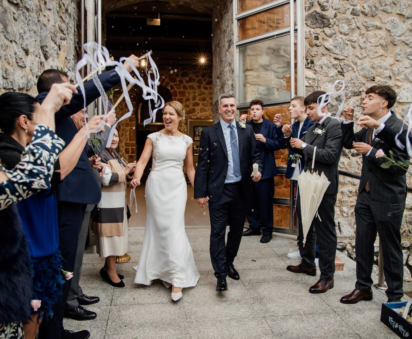 Pareja de recién casados saliendo entre aplausos y serpentinas durante su boda en Cantabria, rodeados de invitados
