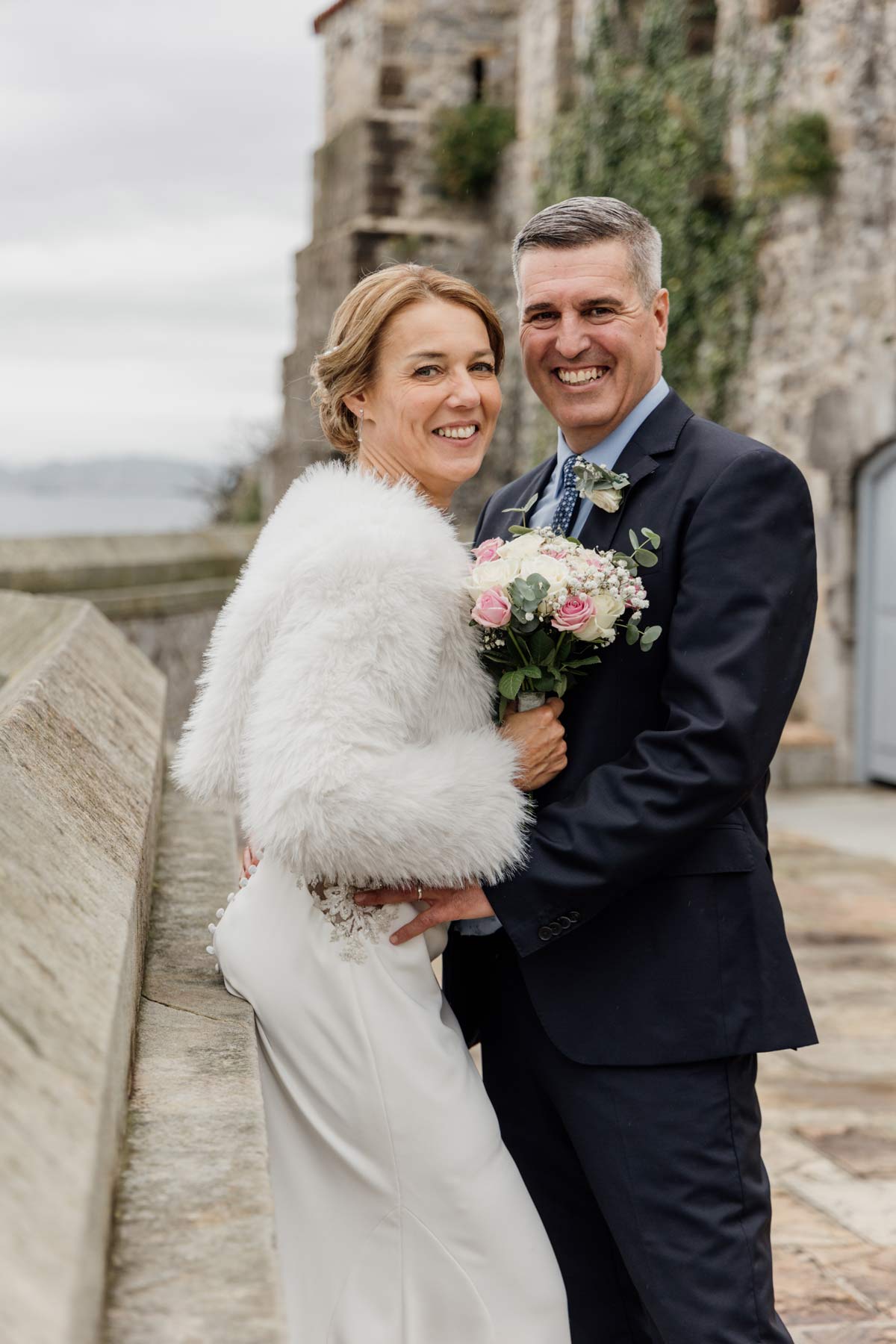 Pareja de recién casados posando al aire libre durante su boda en Cantabria, en un entorno histórico junto al mar