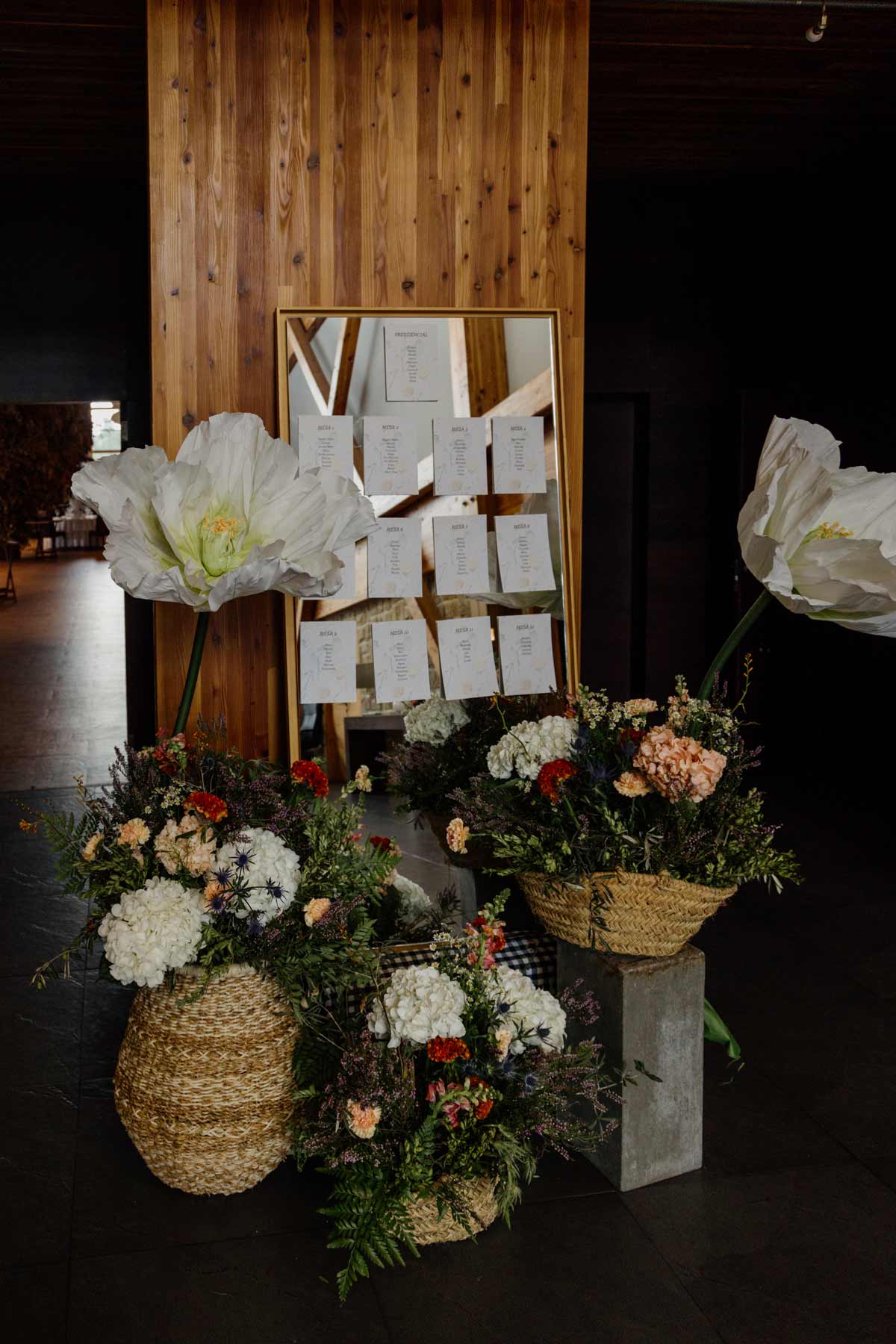 Seating plan de boda decorado con flores y cestos en un salón de celebración, fotografía de boda en Bizkaia.