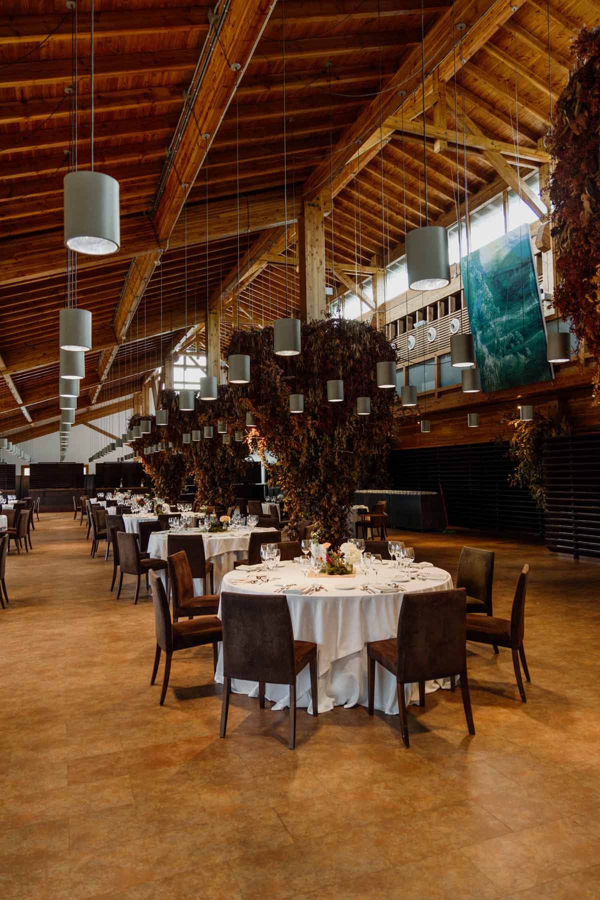 Salón de banquete decorado para una boda, con mesas redondas y detalles florales, fotografía realizada por un fotógrafo de bodas en Bizkaia.