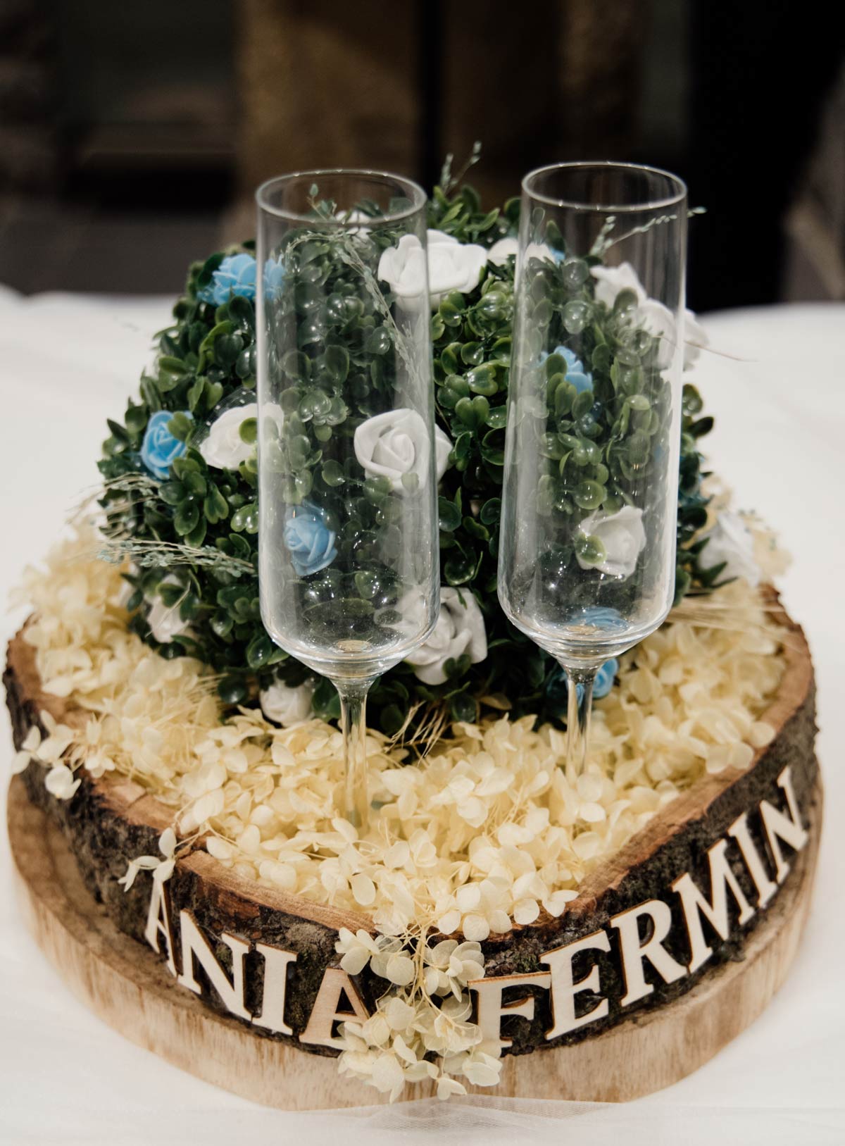 Copas de brindis sobre decoración florasen madera, fotografía de detalles nupciales realizada de por fotógrafo de bodas en Cantabria.