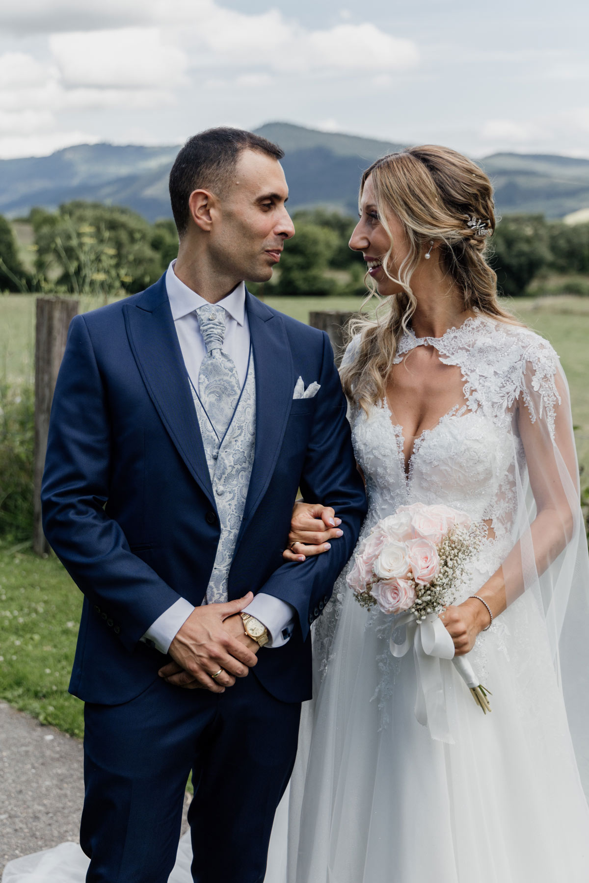 Recién casados posando al aire libre con paisaje montañoso de fondo, fotografiados por un fotógrafo de bodas en Bilbao.