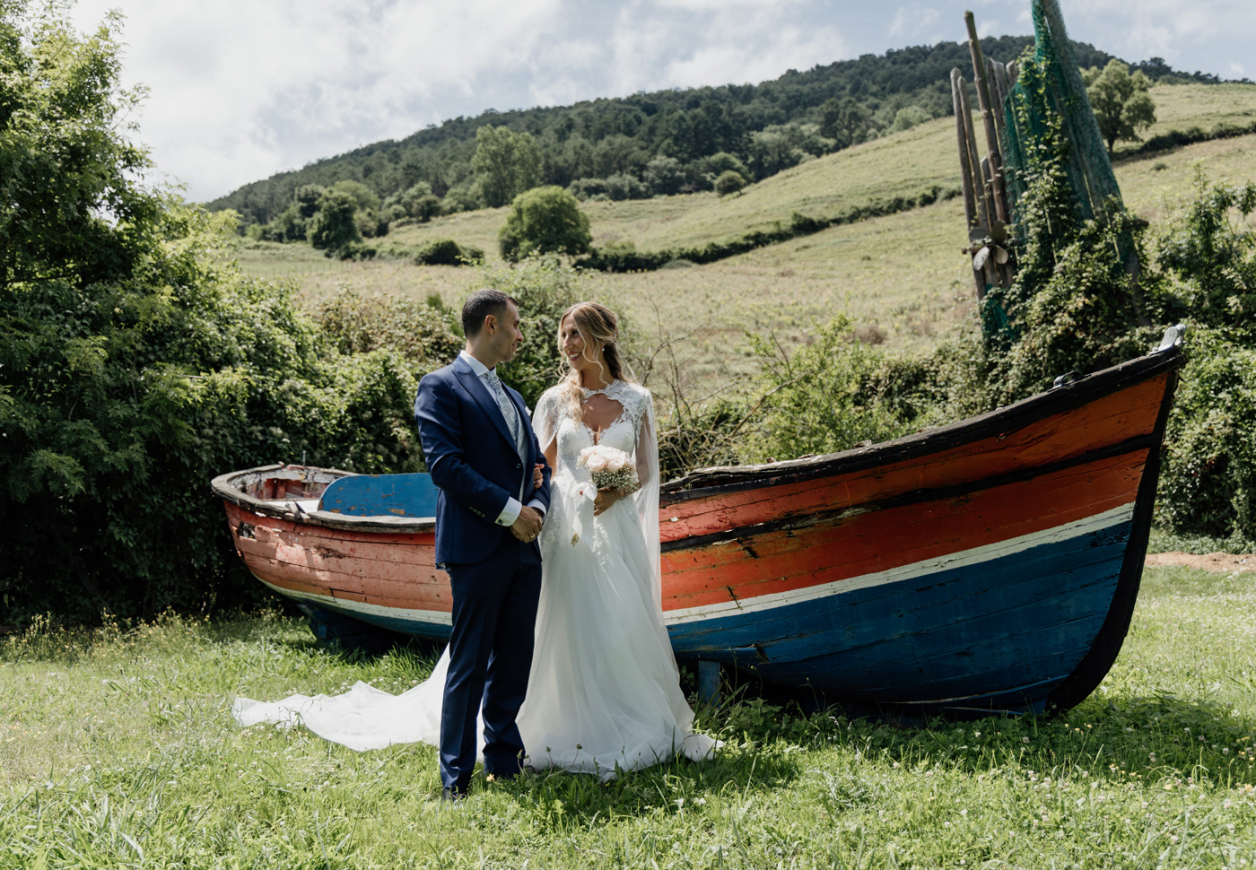Pareja de recién casados posando junto a una barca en un paisaje rural, fotografiada por un fotógrafo de bodas en Bilbao.