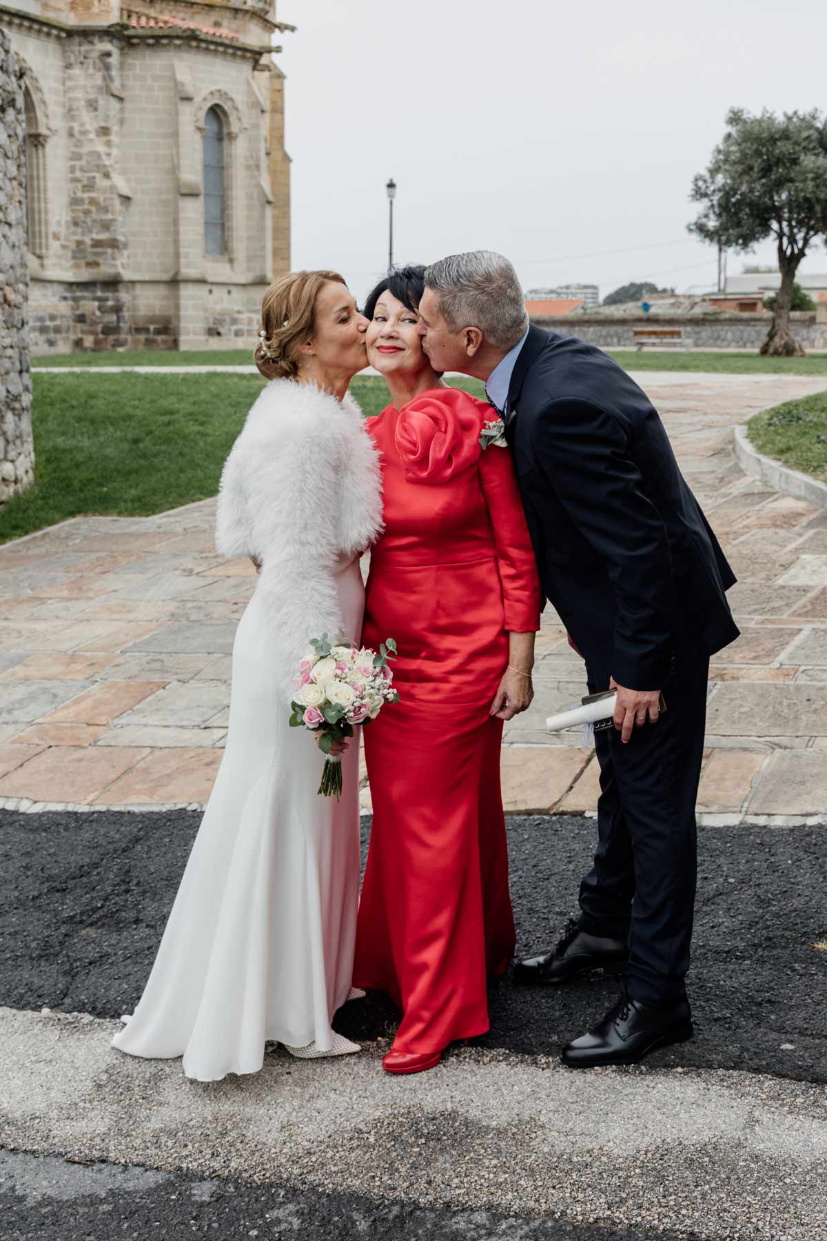 Fotógrafo de bodas en Cantabria captando un momento familiar con la novia y sus padres frente a una iglesia.